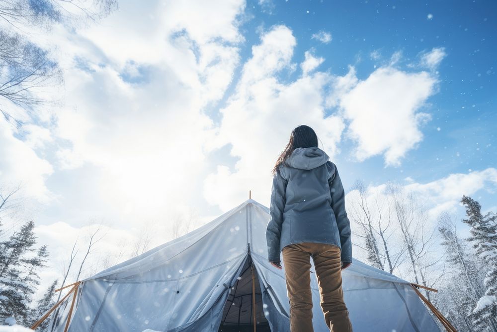 Woman standing in front of tent snow sky outdoors.