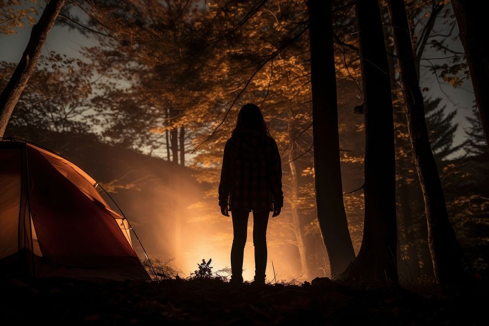 Woman standing in front of tent outdoors camping forest.