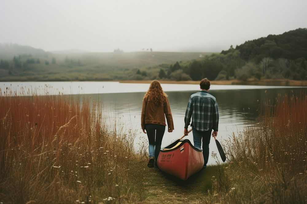 Couple carrying canoe boat together walking adult lake.
