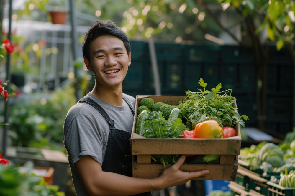 Young Chinese man carrying a vegetable box garden smile gardening.