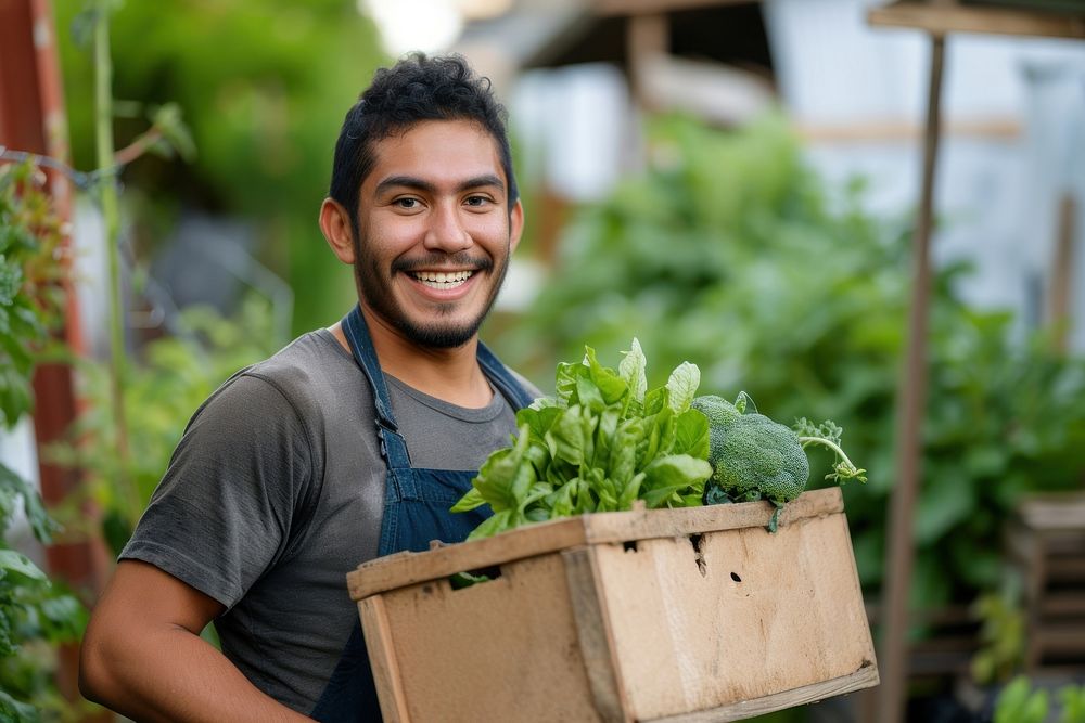 Young Latino man carrying a vegetable box garden adult gardening.