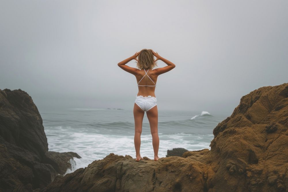 Woman standing on a rock at the beach swimwear outdoors nature.