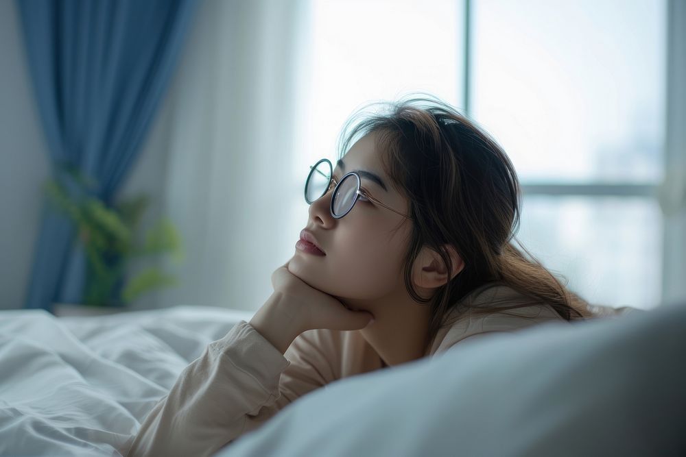 Woman thinking worried glasses bedroom.