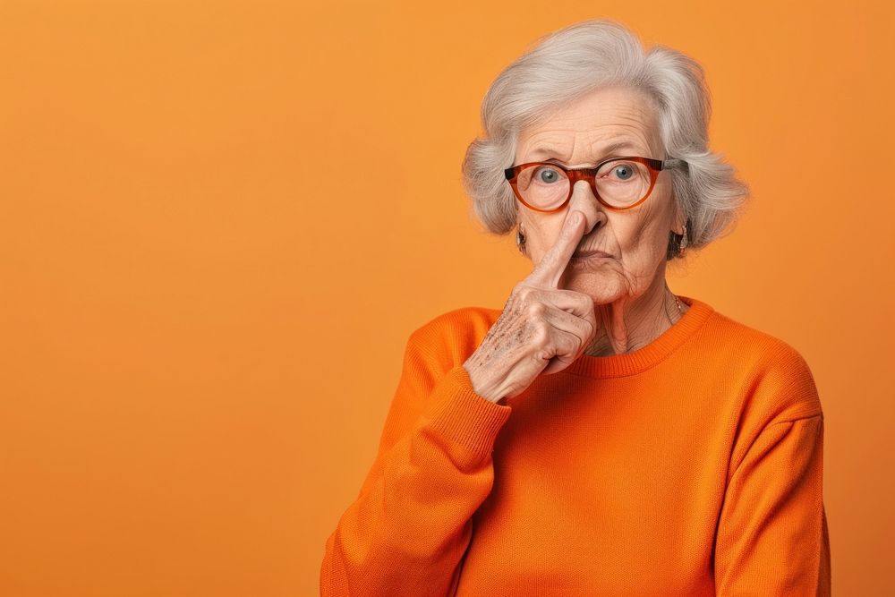 Old woman make silent gesture portrait glasses sweater.