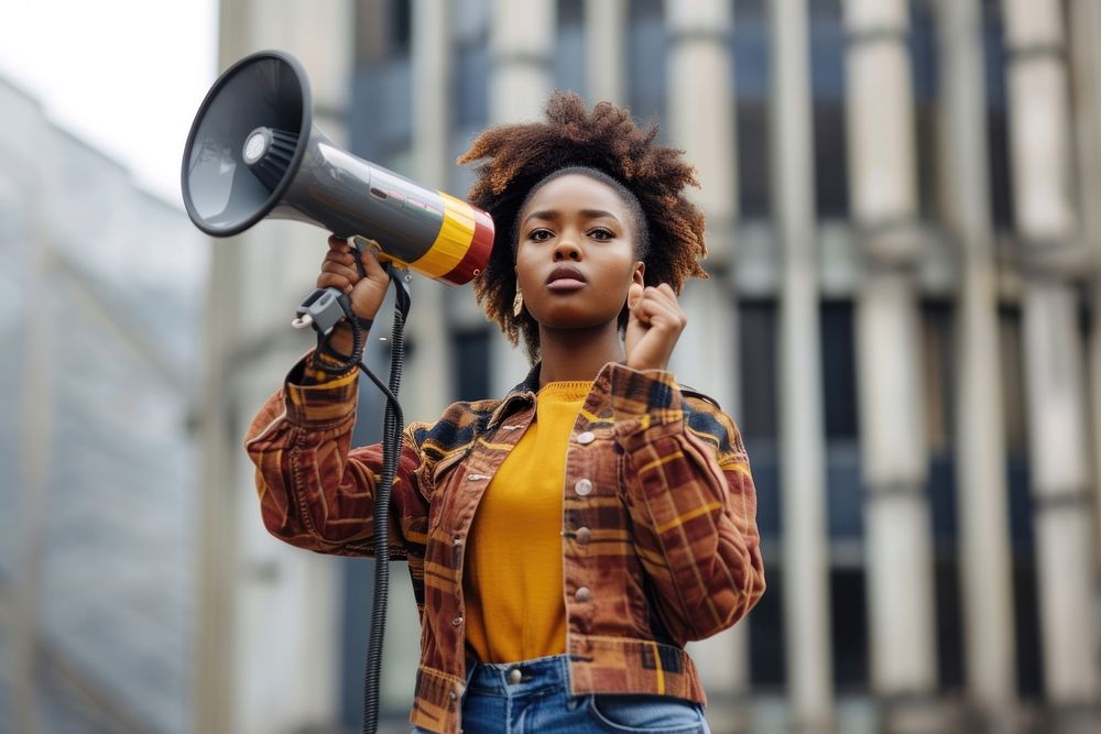 Black Young woman leading a demonstration using a megaphone outdoors individuality architecture.