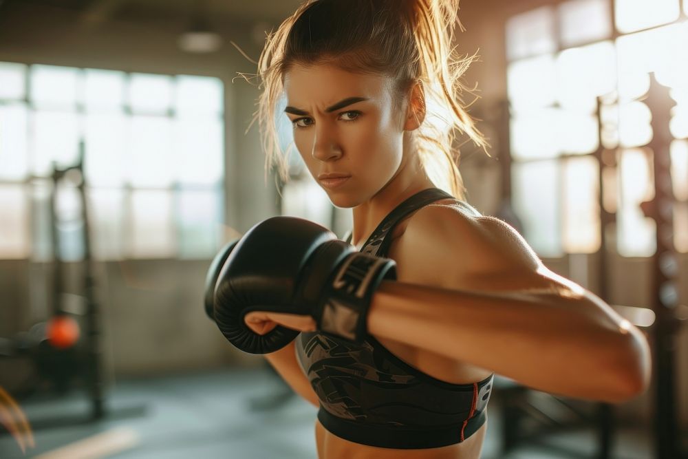 A woman kickboxing in a bright gym to get a workout adult determination concentration.
