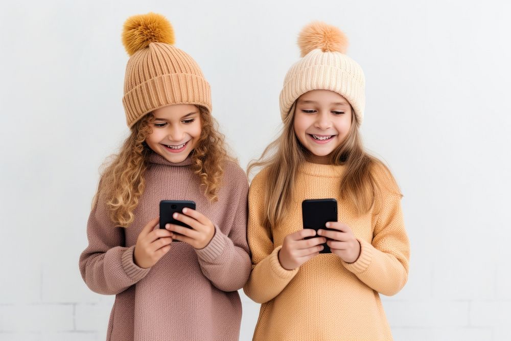 Two girls stand together while holding one phone sweater photo fun.