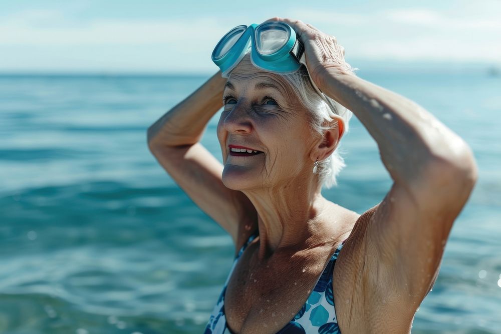 Senior woman standing at the sea in swimming swimwear goggles.