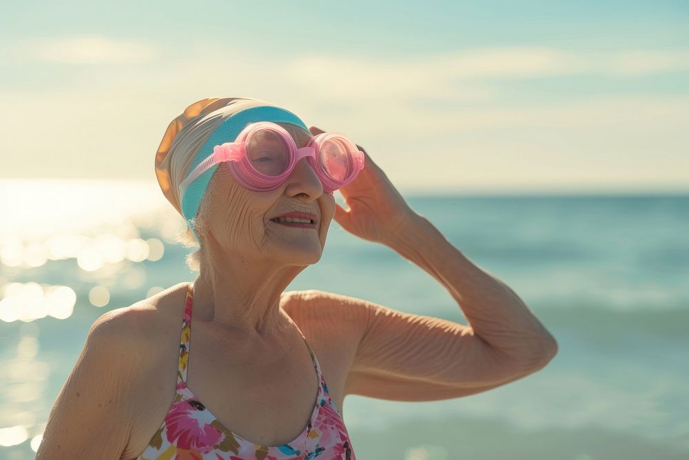 Happy senior woman standing at the sea wearing swimming hat swimwear portrait outdoors.