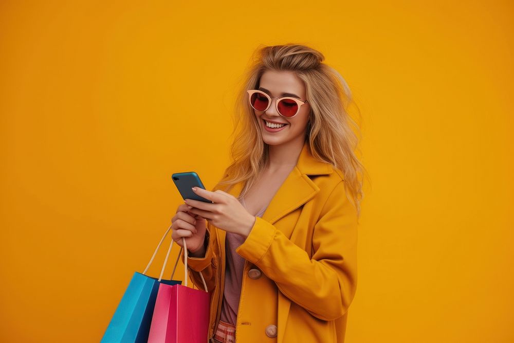 Smiling young lady wear sunglasses using her smartphone while shopping bag handbag adult.