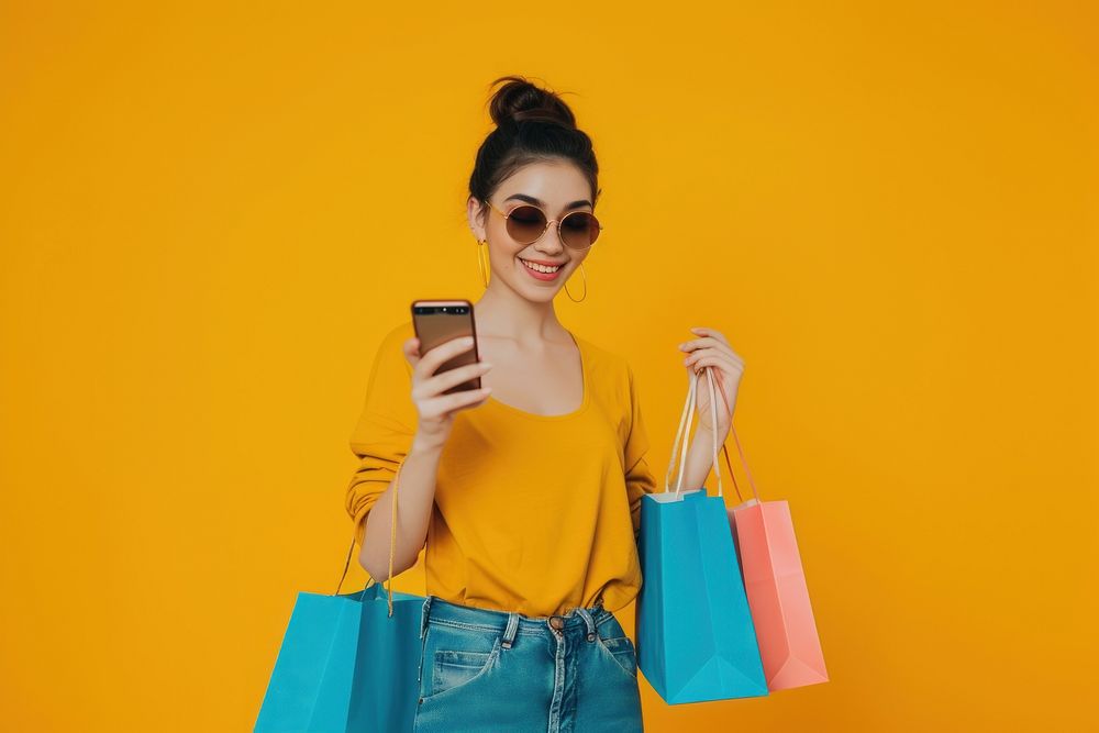 Smiling young lady wear sunglasses using her smartphone while shopping bag handbag adult.
