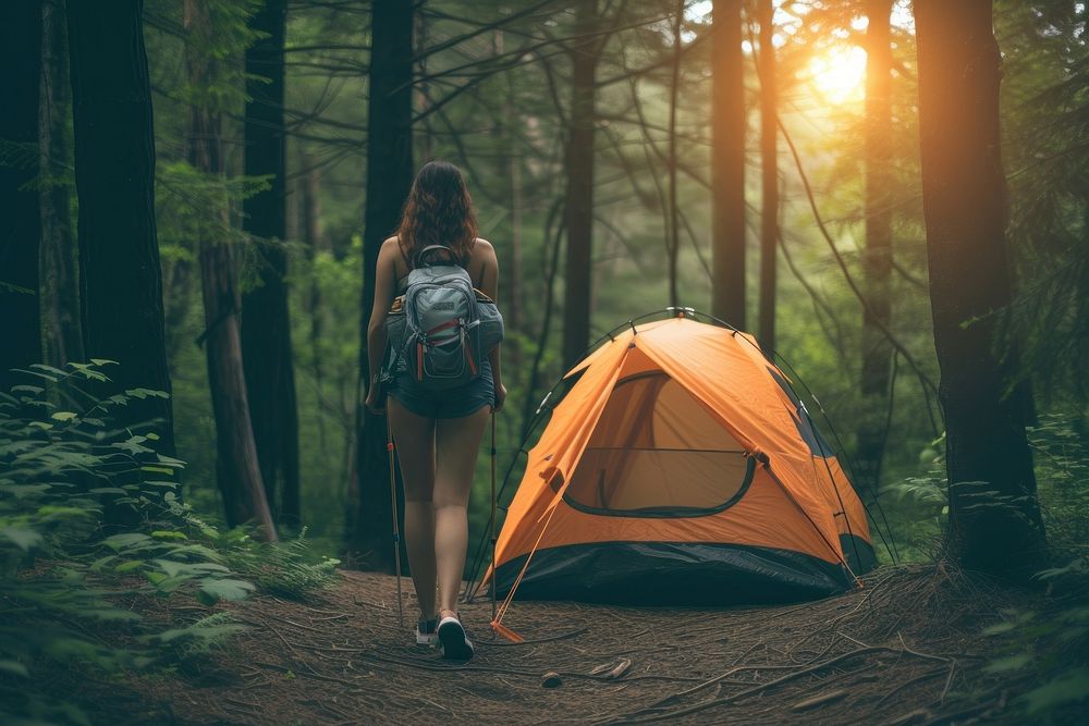 Woman coming out of tent camping in the woods outdoors backpack nature.