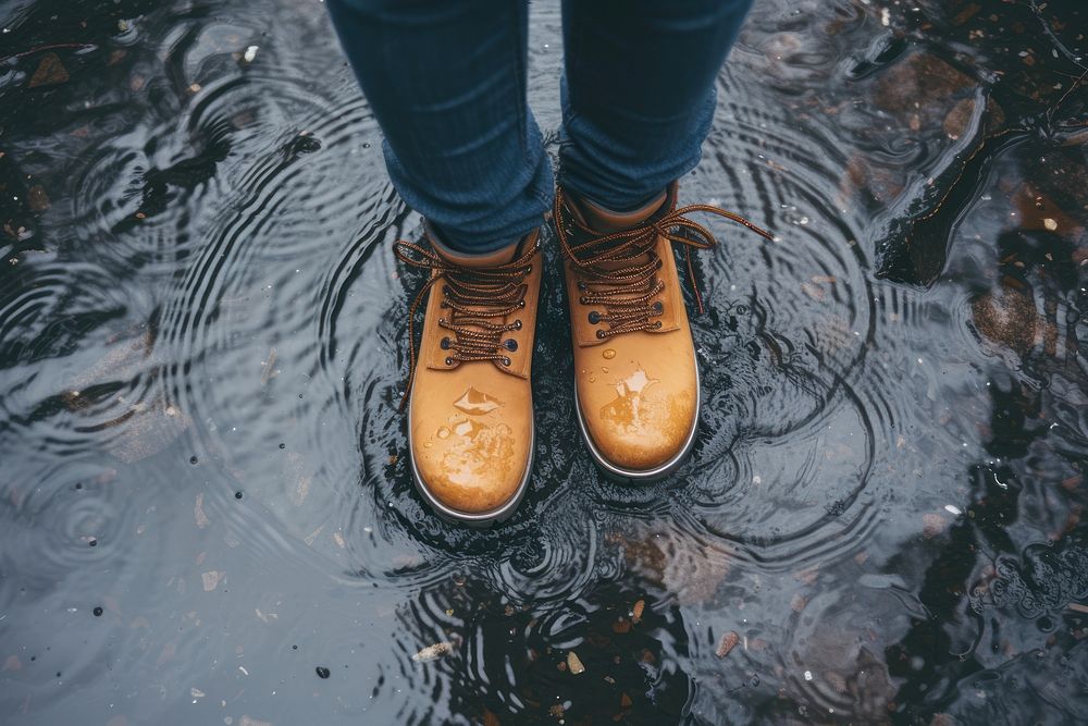 Woman in tourist waterproof hiking boots walking on water in puddles in the rain footwear outdoors shoe.