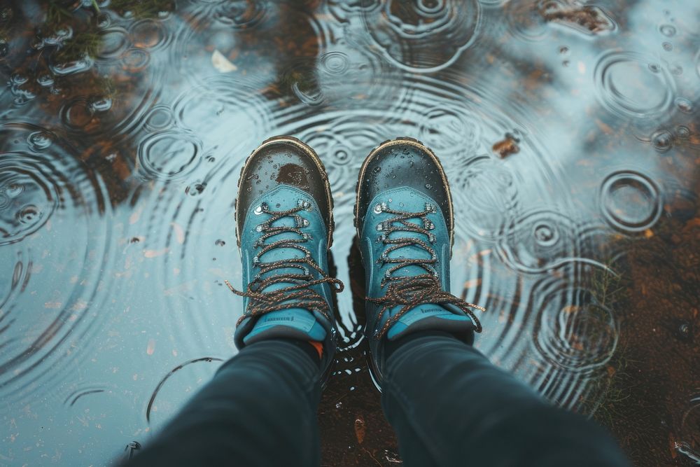 Woman in tourist waterproof hiking boots walking on water in puddles in the rain footwear outdoors nature.