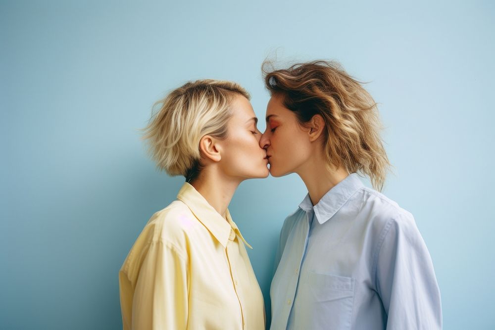 A lesbian couple wearing colorful shirts kissing adult photo.