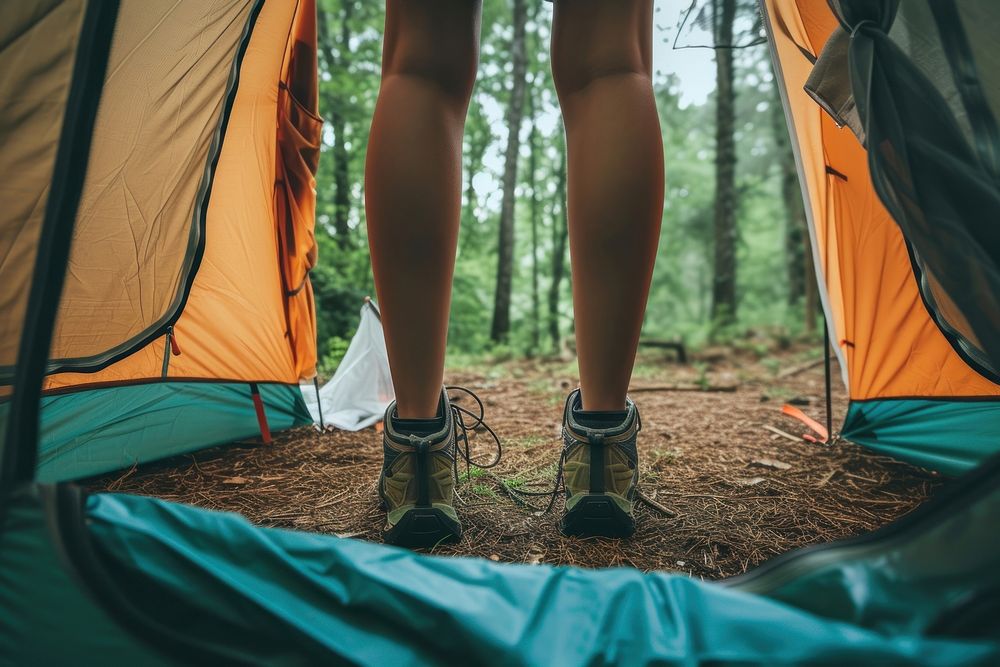 Close up leg woman standing against coming out of tent camping in the woods outdoors nature shoe.