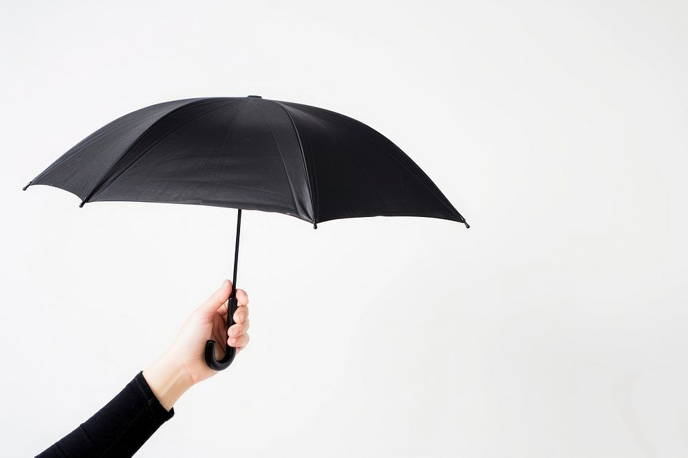 Hand holding black color umbrella white background protection technology.