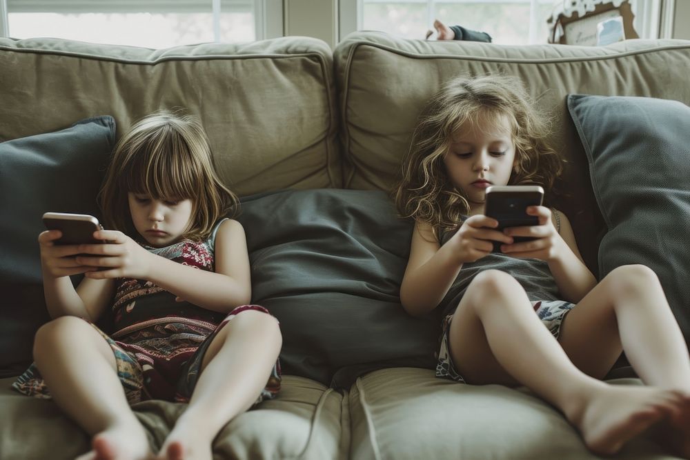 Children using their cell phones on the couch furniture togetherness electronics.