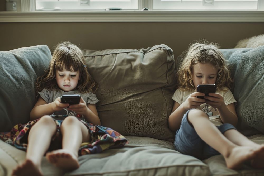 Children using their cell phones on the couch furniture togetherness electronics.