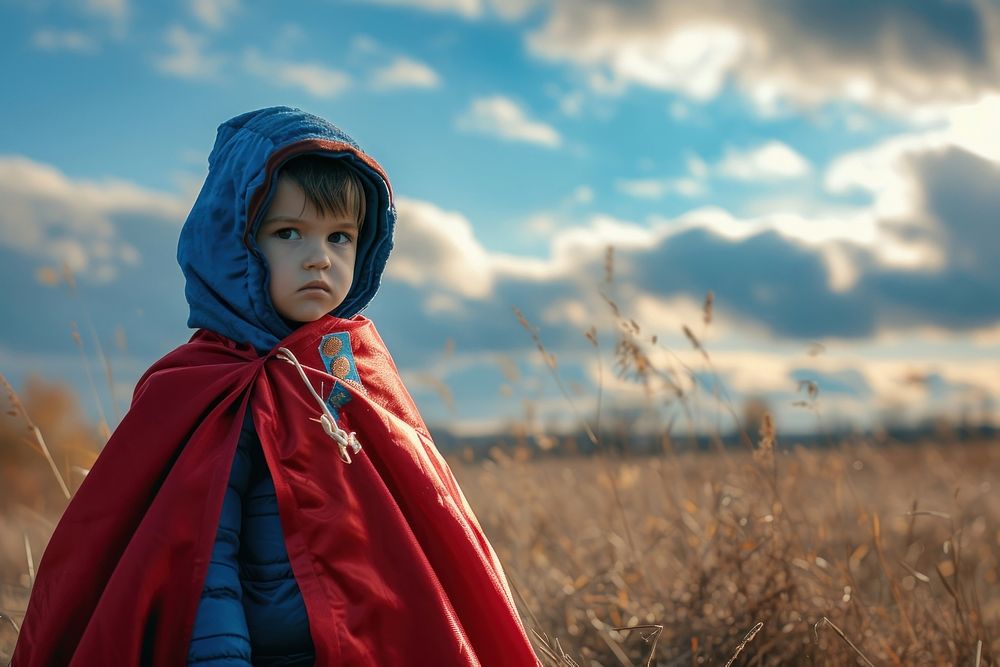 Small child in a superhero costume and coat photography hood landscape.