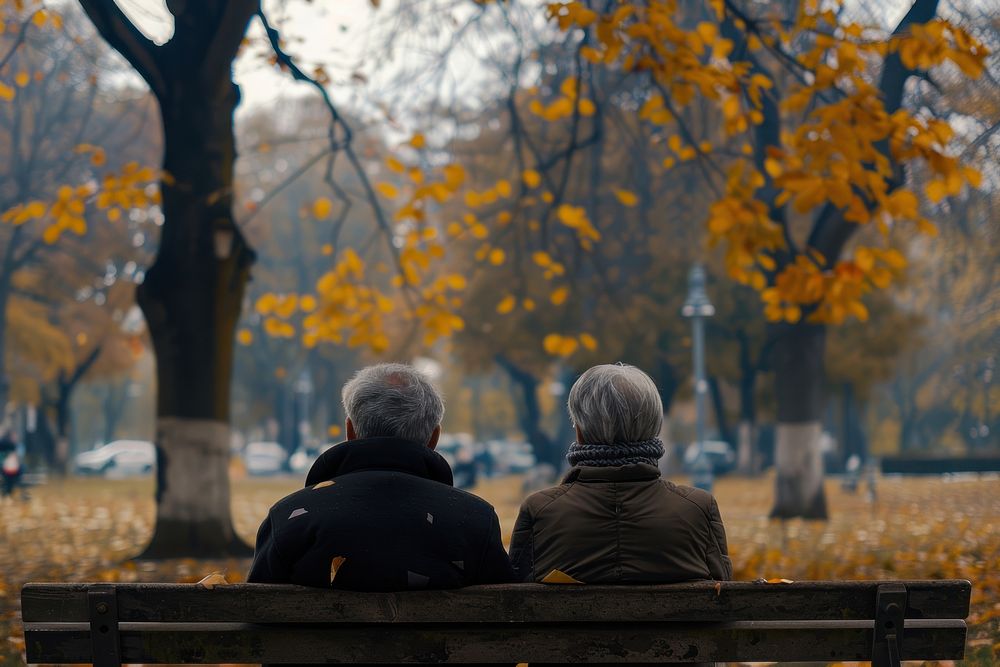 Happy elderly couple sitting outdoors autumn.