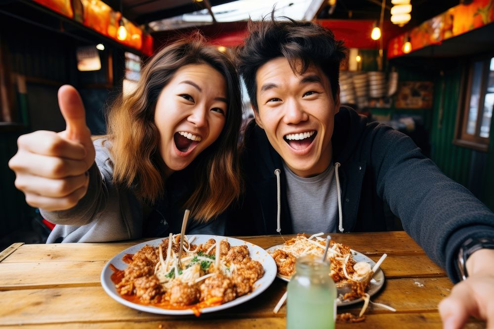 Two vloggers film a video with their street food laughing meal dish.