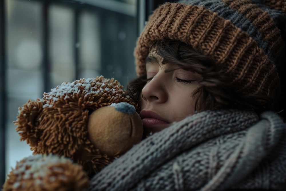 Person holding teddy bear sleeping contemplation homelessness.