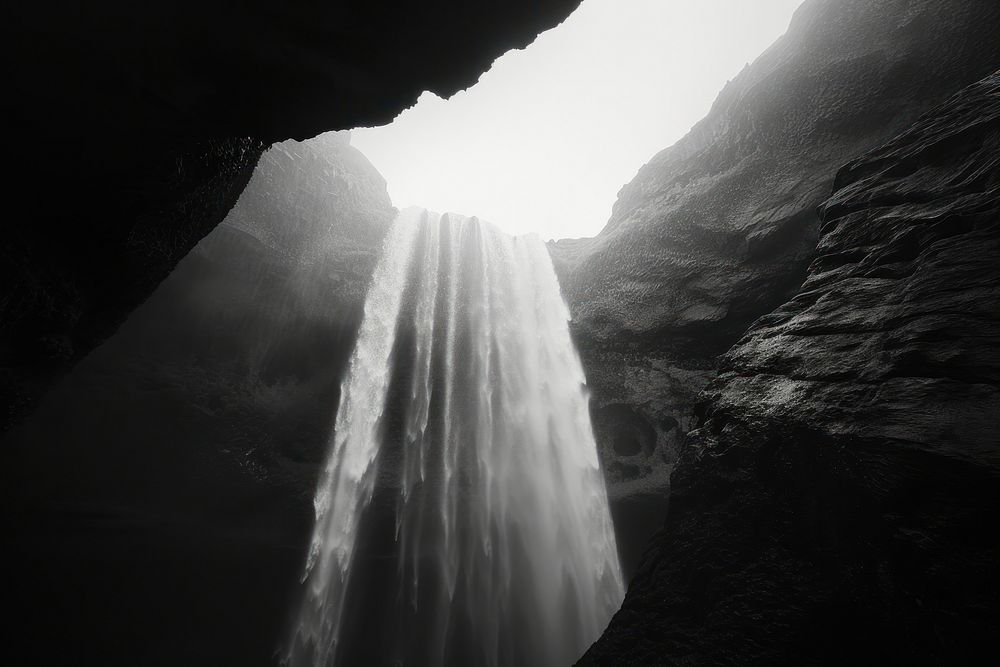 A waterfall coming from the top of a cave outdoors nature light.