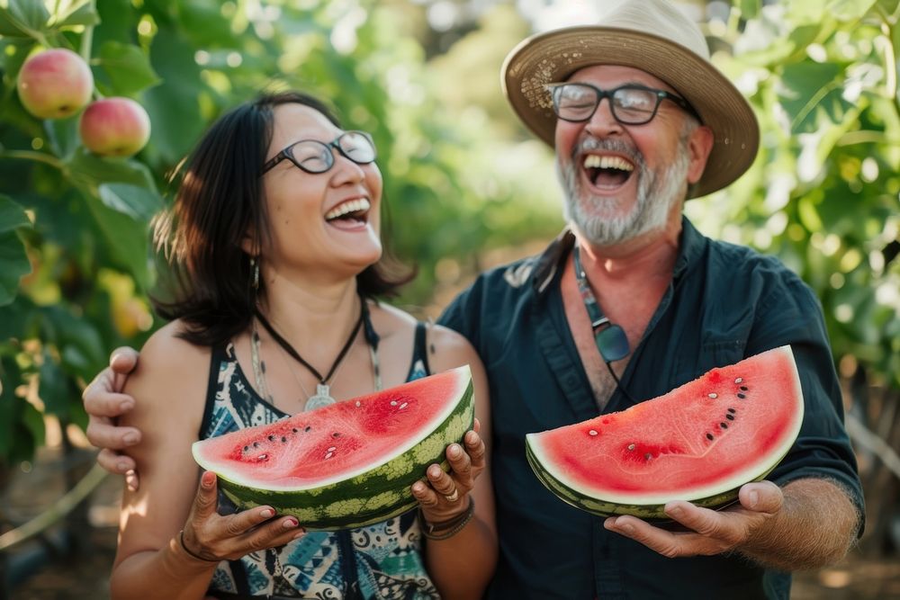 Middle-aged couple laughing watermelon holding glasses.