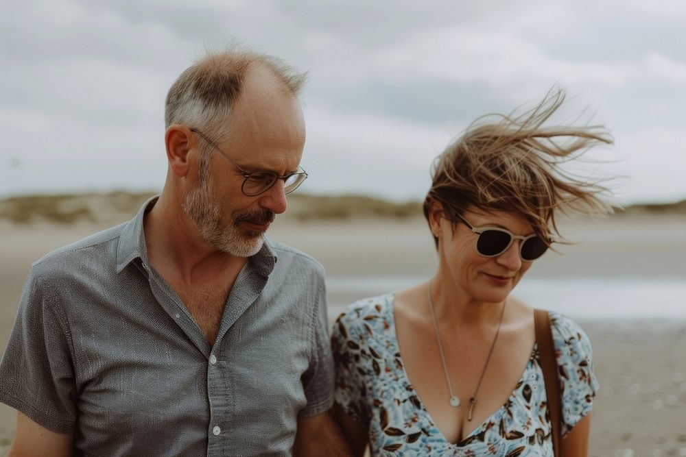 Middle-aged couple walking together beach sunglasses portrait.