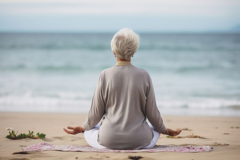 Elderly woman doing yoga sitting sports beach.