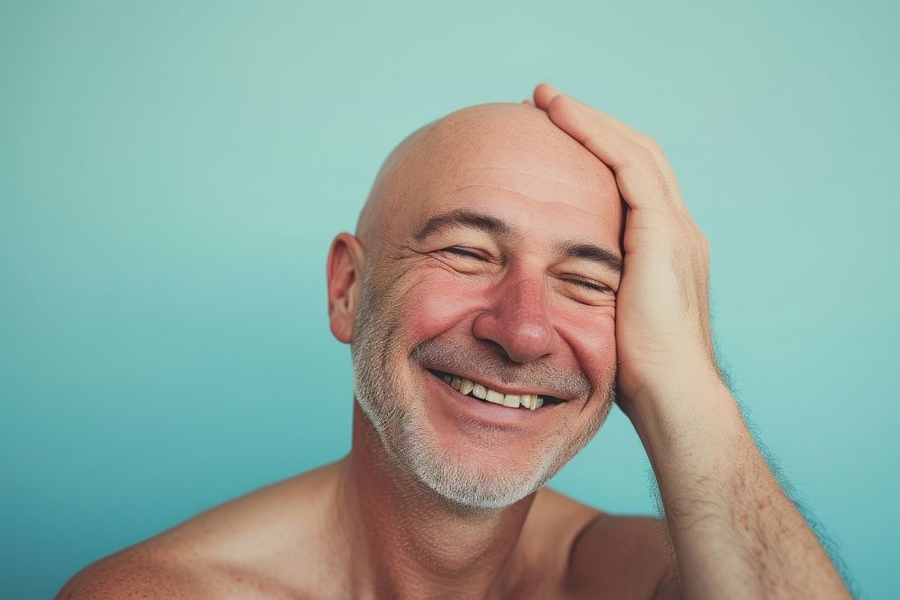 Bald middle age man touching shaved head smile laughing adult.