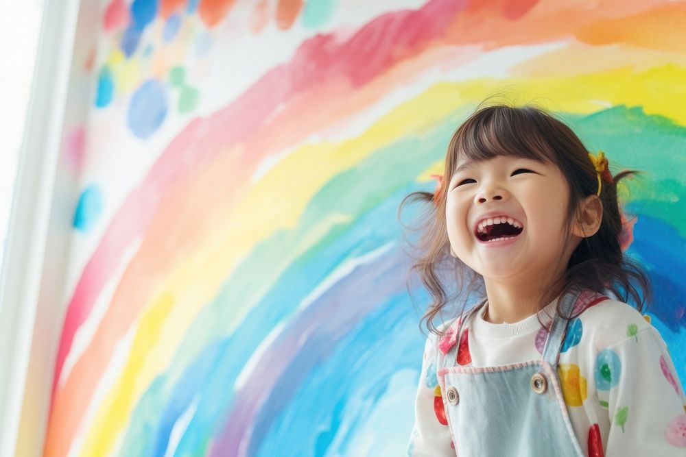 Little girl is painting laughing rainbow smile.