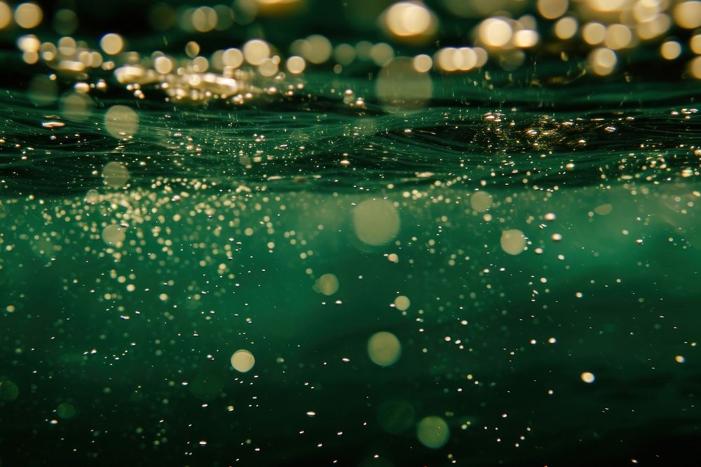 Bubbles and bokeh underwater in clear green ocean sea outdoors glitter.