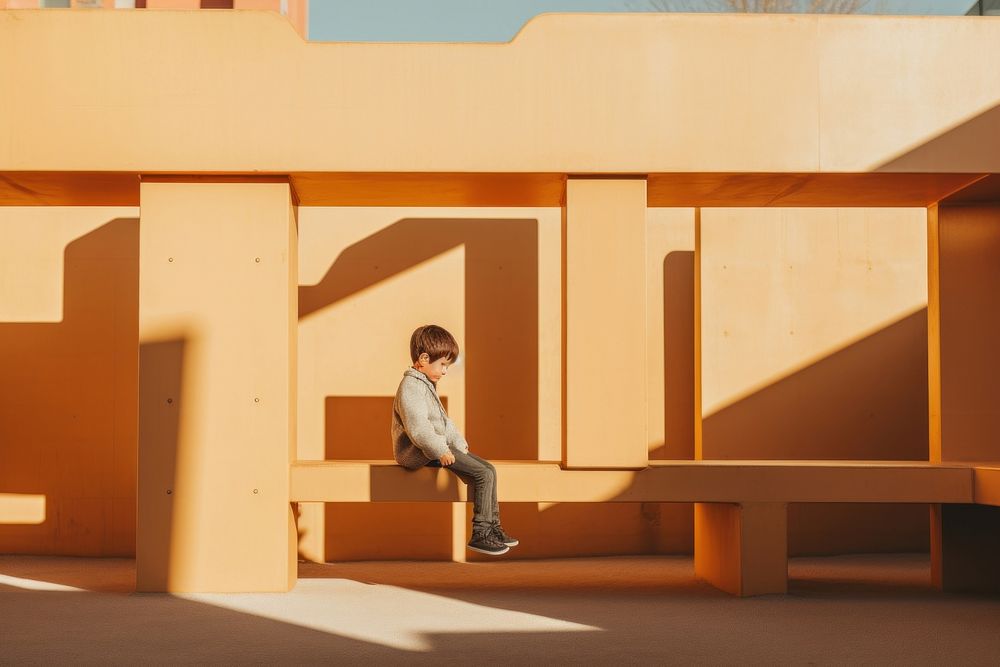 A kid with autism playing in the playground shadow architecture building.