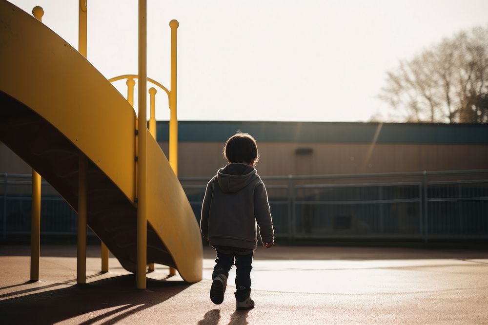 A kid with autism playing in the playground outdoors walking looking.