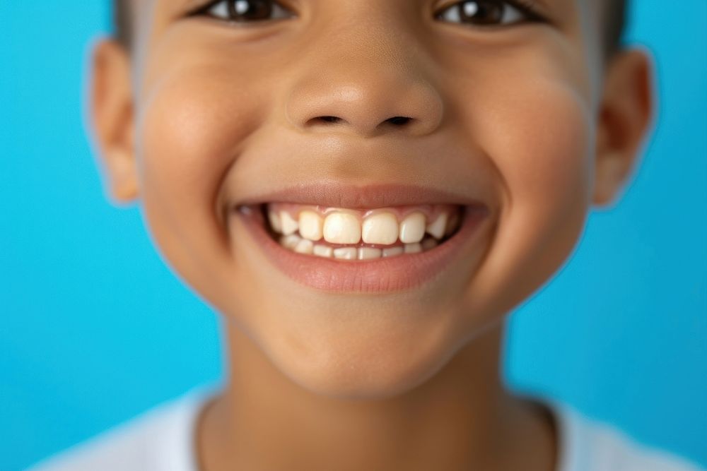 6 year old boy showing beautiful white smile teeth skin blue.