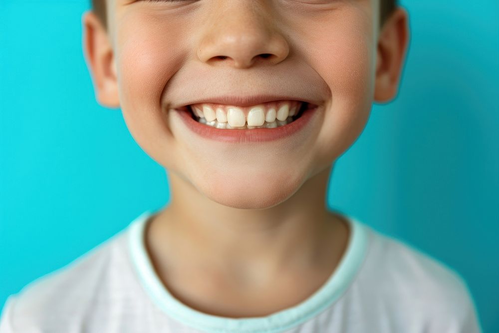6 year old boy showing beautiful white smile teeth skin blue.