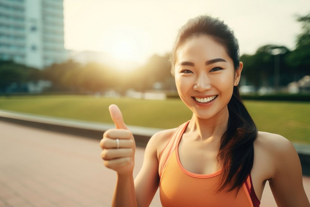 An asian athlete taking selfie while jogging in public park finger smile hand.