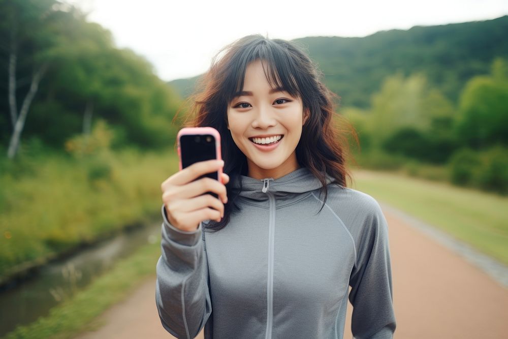 An beautiful asian athlete taking selfie while jogging in public park portrait smile adult.