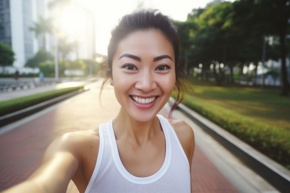 An beautiful asian athlete taking selfie while jogging in public park smile architecture exercising.