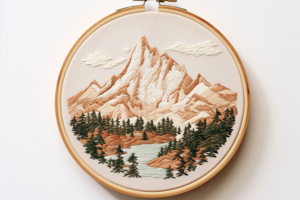 Embroidery hoop with mountauins scene in embroidery style pattern representation cross-stitch.