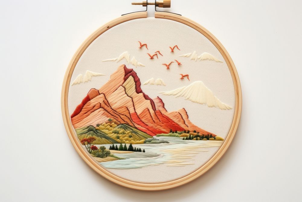 Embroidery hoop with mountauins scene in embroidery style pattern locket representation.