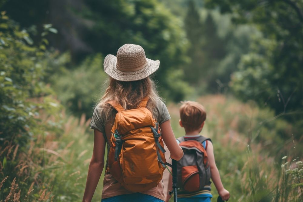Small children with mother hiking backpack outdoors nature.