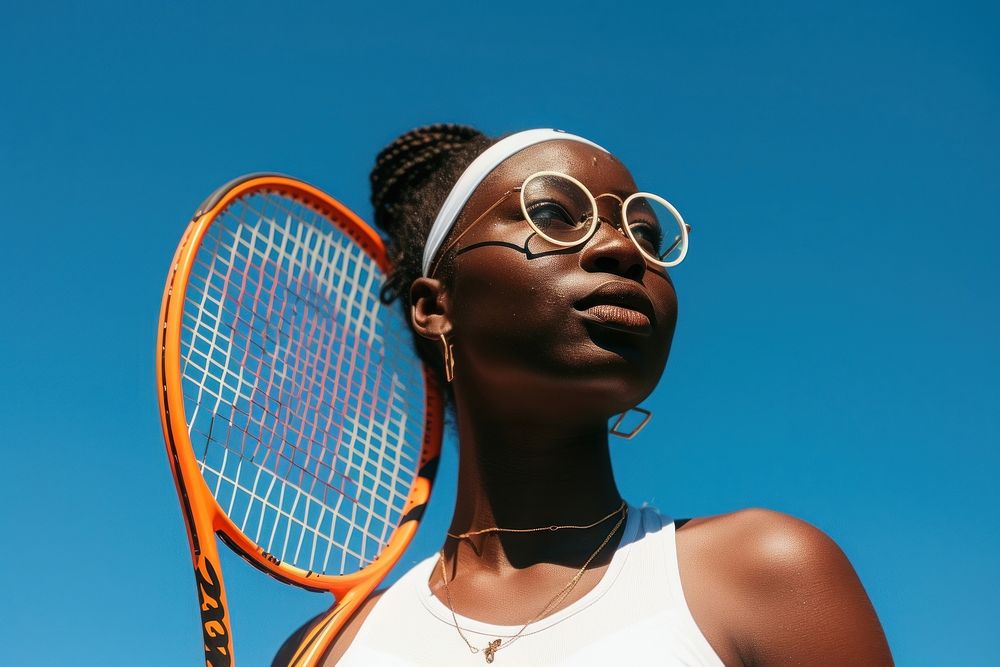 Black woman holding tennis racket outdoors sports day.