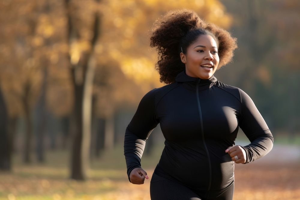 Plus size black woman in sport wear running in park outdoors jogging sports.