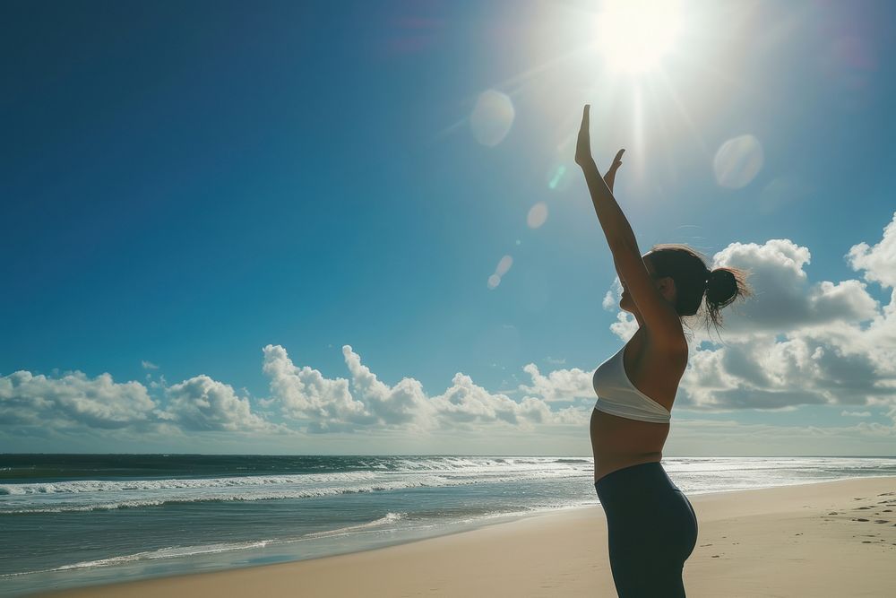 Woman doing yoga outdoors beach sunny.