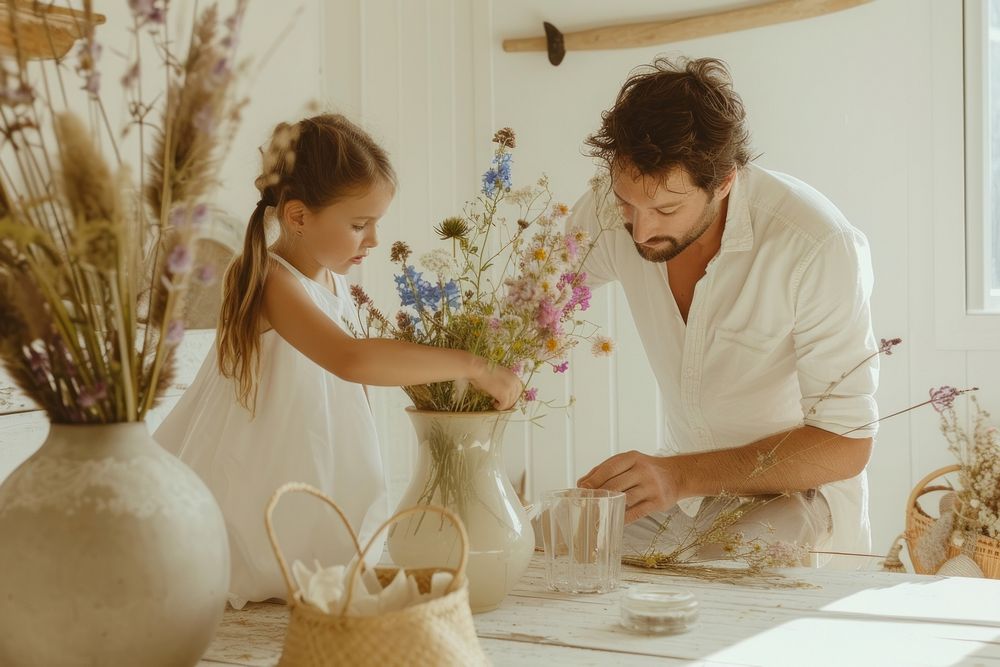 A girl and dad arrange wild flowers to a vase adult child togetherness.