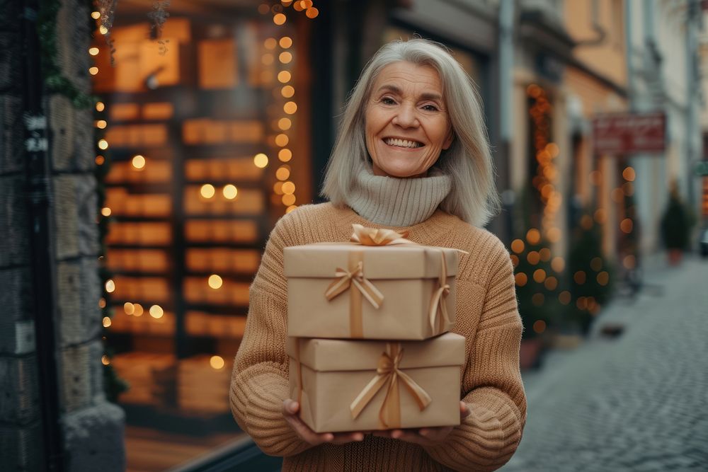 A joyful mature woman with a stack boxes sweater holiday smile.