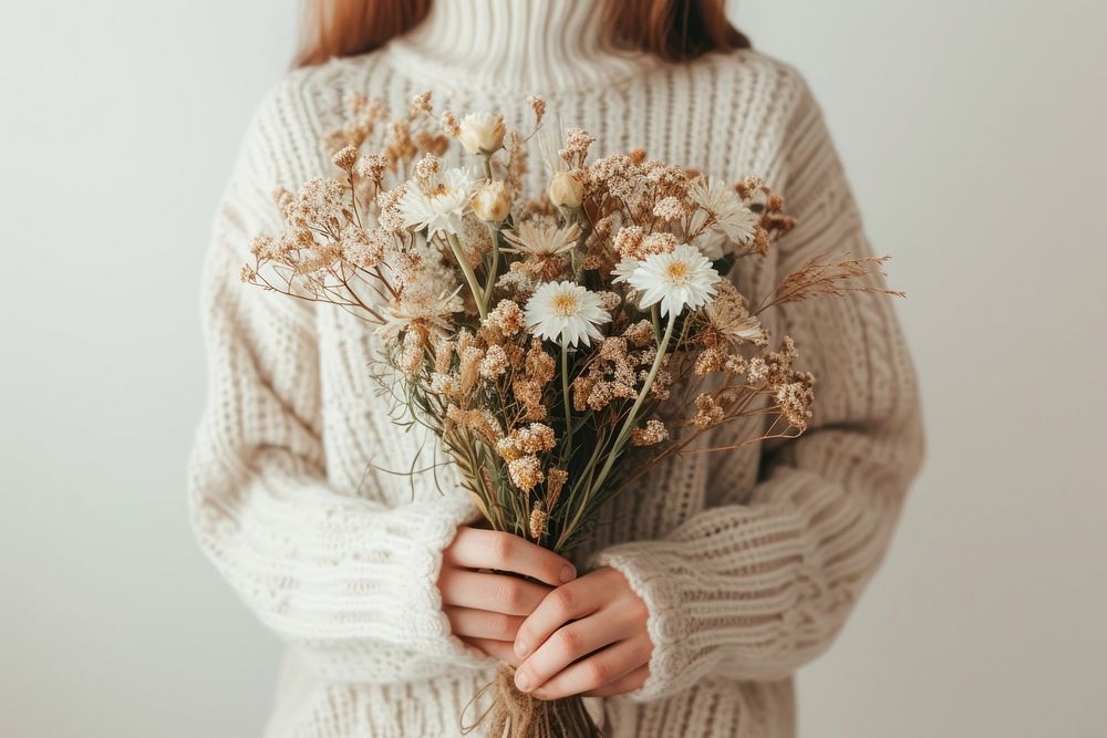 Person holding flowers sweater plant white.